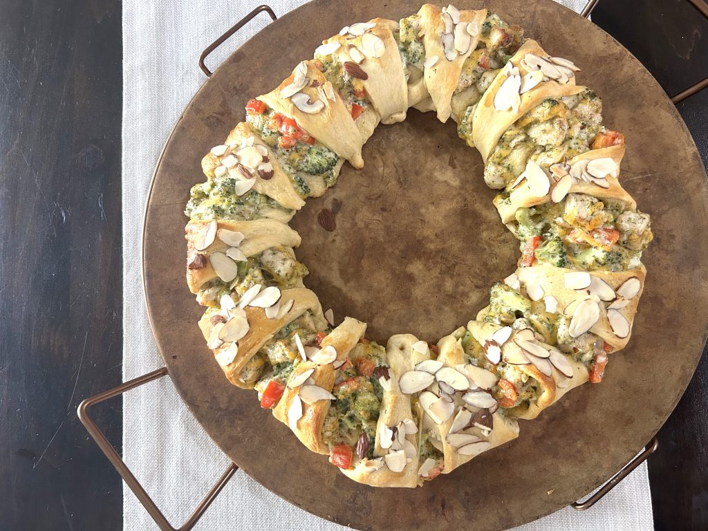 A wooden baking stone with an assembled and baked chicken broccoli braid ready to eat