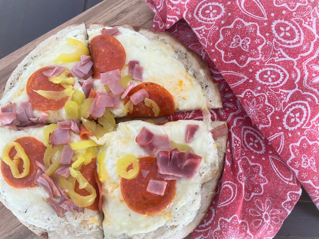 A personal pan homemade pizza cut in 4 on a wooden cutting board