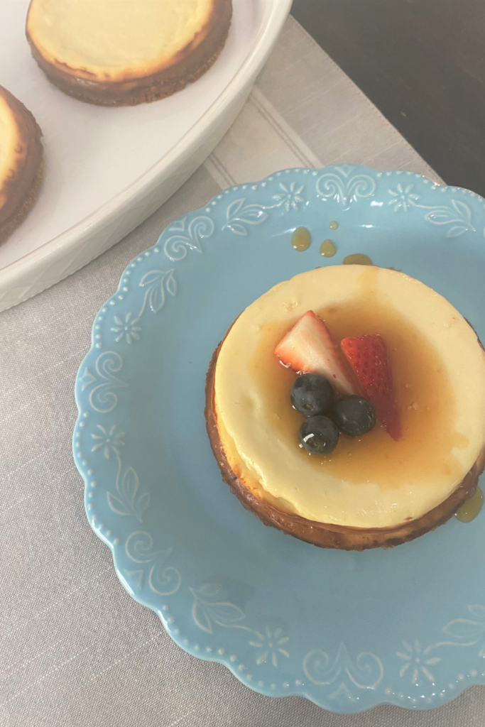 Mini Cheesecake topped with fresh berries and caramel sauce on a pretty pastel blue plate