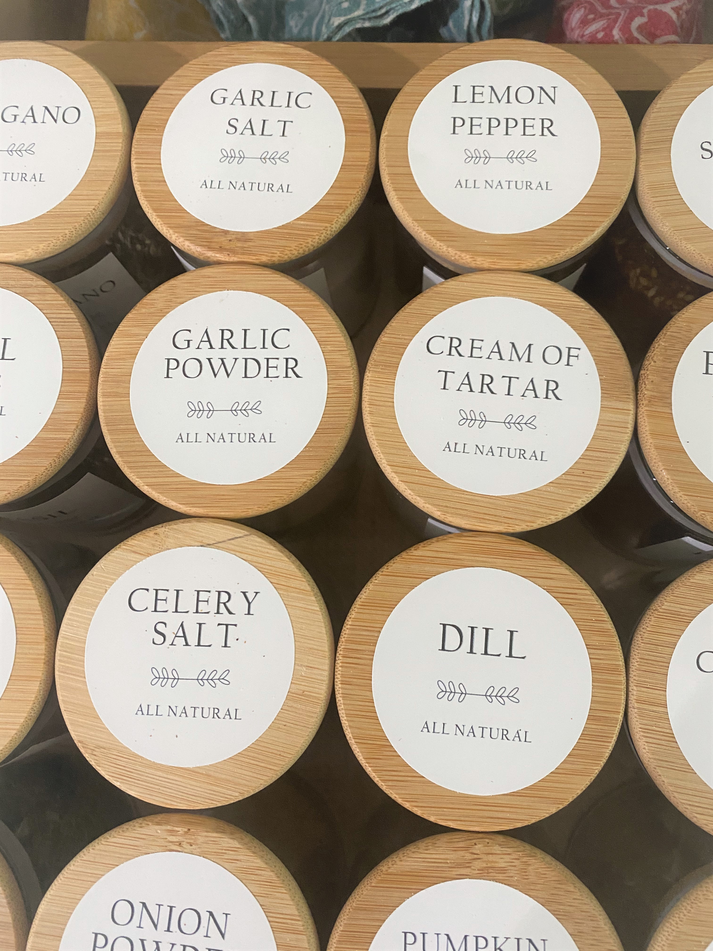 A close up picture of several spice jars with pretty labels arranged in rows in a drawer