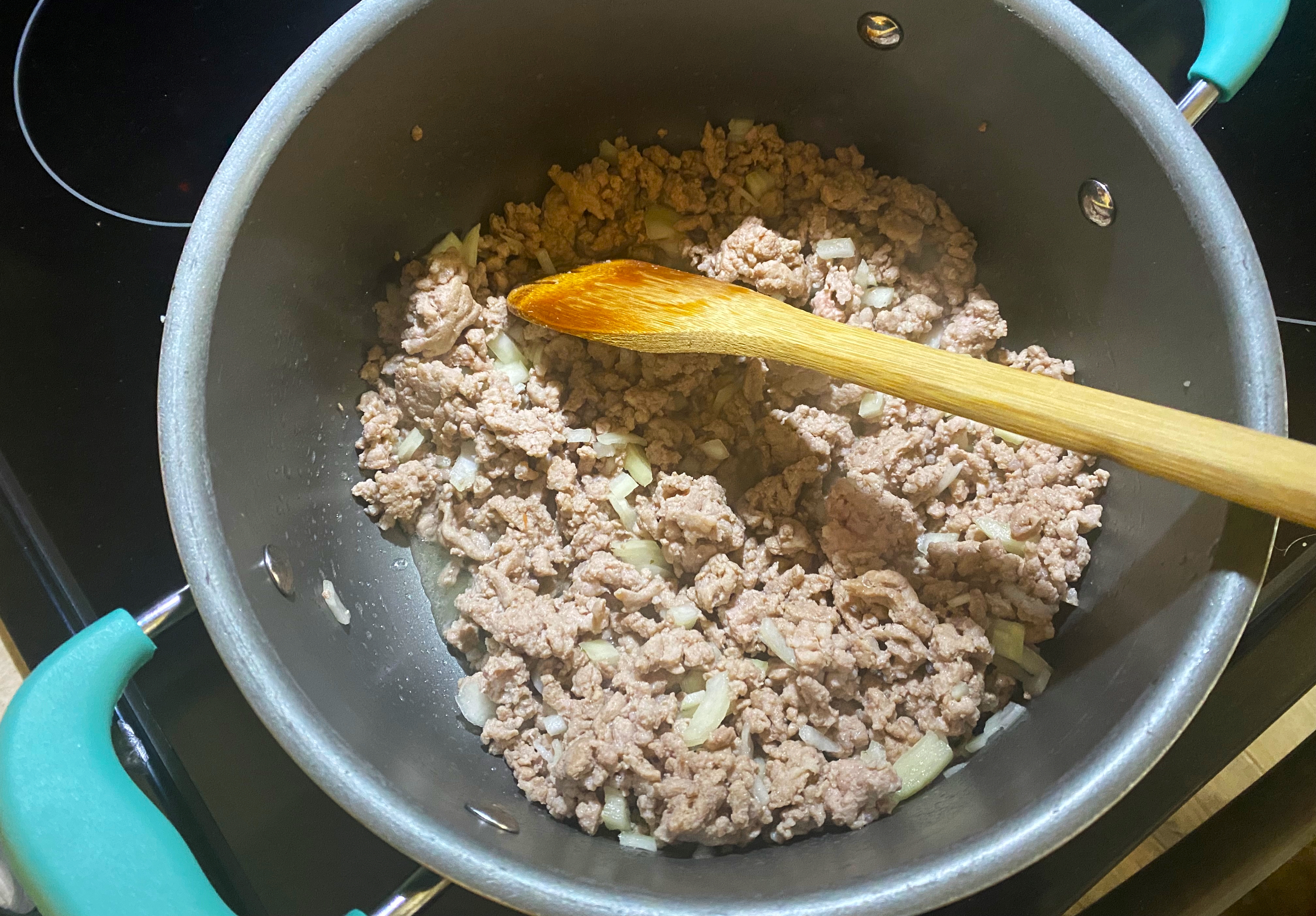 Ground sausage and onion cooking in a stockpot on a stove top