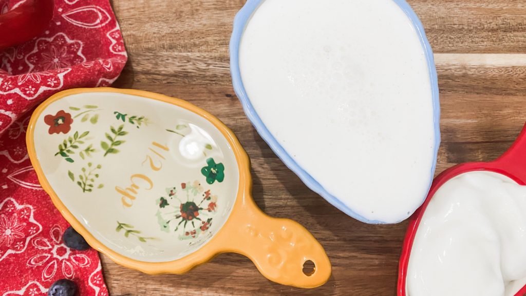 Three colorful measuring cups filled with oil, buttermilk and yogurt to make homemade buttermilk blueberry and yogurt waffles