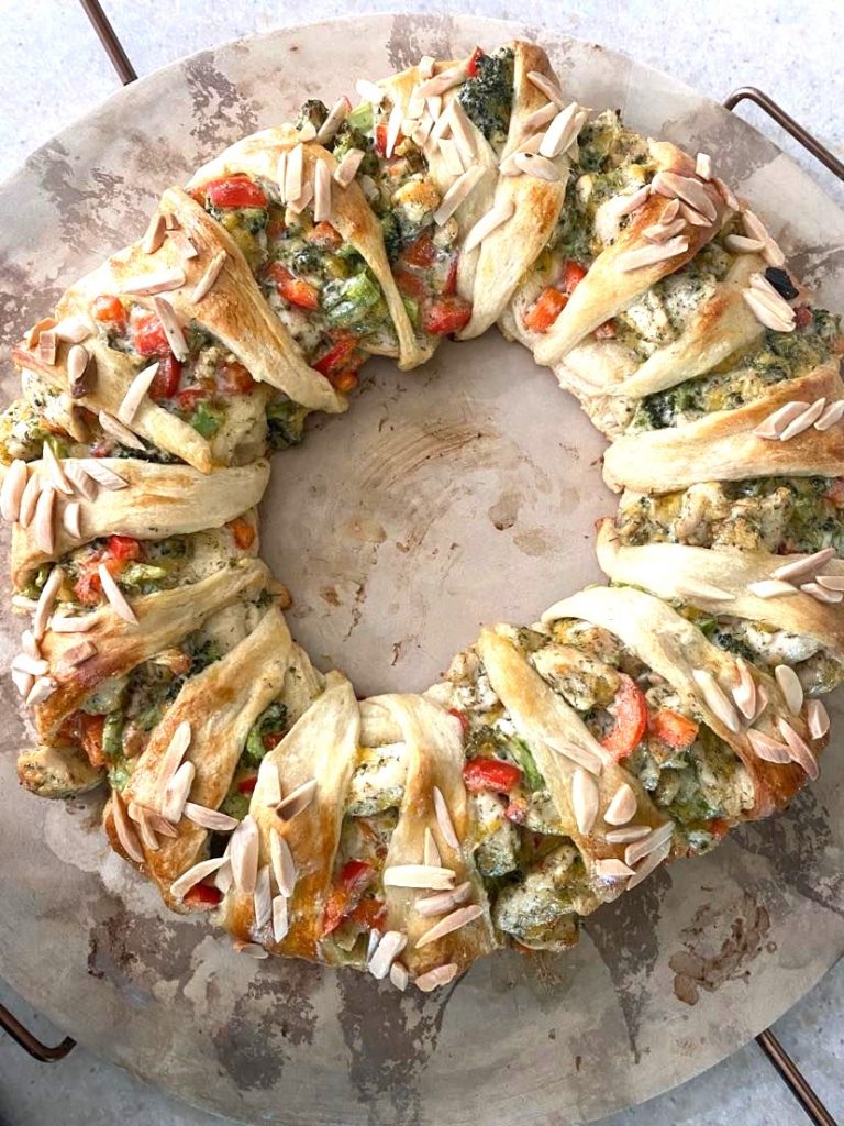 A fullly assembled and baked chicken broccoli braid on a round baking stone